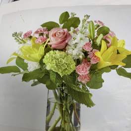 Pink roses and yellow lilies arranged in a glass vase