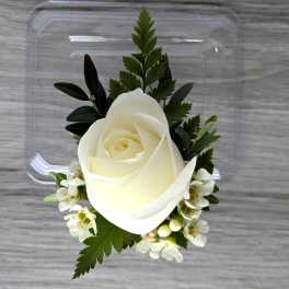 White rose boutonniere with small white blossoms and greenery
