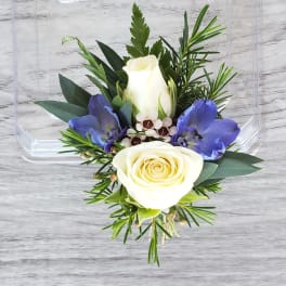 White rose boutonniere with blue flowers and greenery