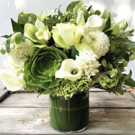 Green and white floral arrangement in a dark glass vase