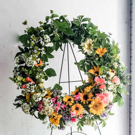 Large floral wreath with mixed blooms on a black stand