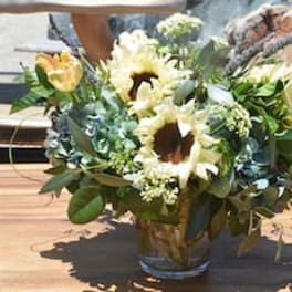 Bouquet of sunflowers and pale yellow tulips in a glass vase