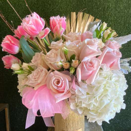 Pink roses, fringe tulips, and white hydrangeas in a gold vase with a pink bow
