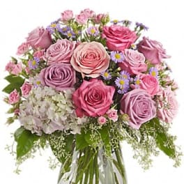 Pink and lavender roses arranged in a clear glass vase