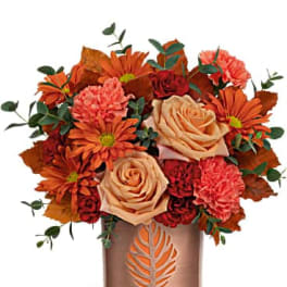Orange and peach bouquet in a copper vase