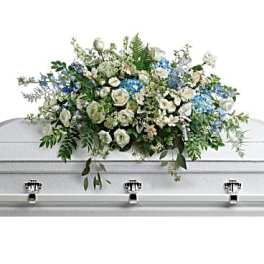 White casket spray with blue flowers and greenery