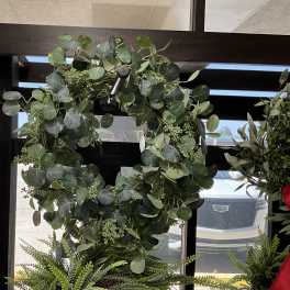 Large green wreath with round leaves hanging in a window display