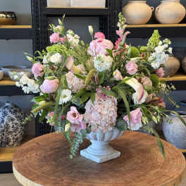 Large pastel floral arrangement in a stone pedestal vase