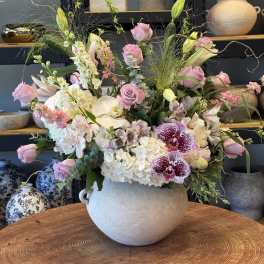 Large pastel flower arrangement in a round ceramic vase