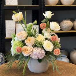 Pastel floral arrangement in a gray vase with roses, hydrangea, and green accents