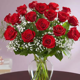 Arrangement of red roses with white filler flowers in a clear glass vase