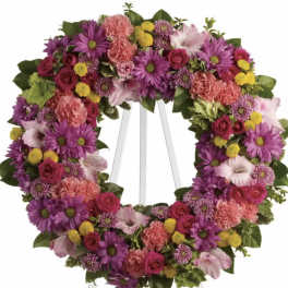 Heart-shaped floral wreath on a white easel with pink, purple, and yellow flowers