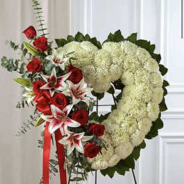Heart-shaped floral tribute with red roses and white lilies on a stand