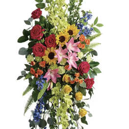 Tall standing floral spray with roses, lilies, sunflowers, and blue accents