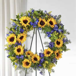 Sunflower wreath with blue and yellow flowers on a black stand