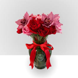 Bouquet of red and pink roses with pink orchids in a glass vase