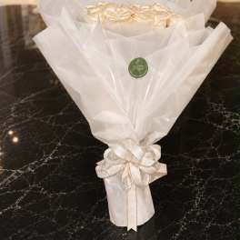 Bouquet of cream roses wrapped in white paper with a ribbon