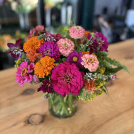 Bright mixed bouquet of pink, orange, and purple flowers in a glass vase