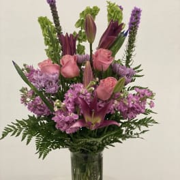 Pink roses and purple lilies in a clear glass vase