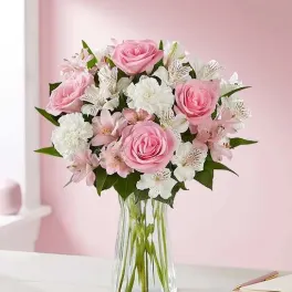 Pink roses and white flowers arranged in a clear glass vase