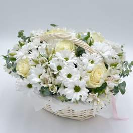 White daisies and cream roses in a wicker basket with a ribbon