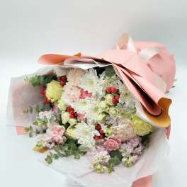 Bouquet of white and pale pink flowers wrapped in pink paper