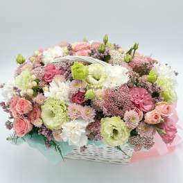 Pastel bouquet of pink, white, and green flowers in a white basket