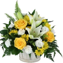 Yellow roses and white lilies arranged in a white container