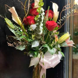 Bouquet of red roses and white lilies with greenery and a pale ribbon