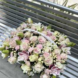 Handheld bouquet of pale pink and white flowers with a braided handle