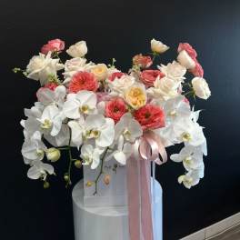 Large white orchid and pink rose arrangement in a white box with pink ribbon