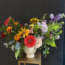 Colorful mixed bouquet in a white vase with zinnias and daisies