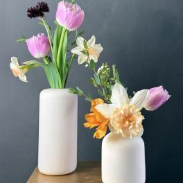 Two small floral arrangements in white vases with pink and white blooms