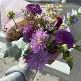 Handheld bouquet of purple flowers with small white daisies