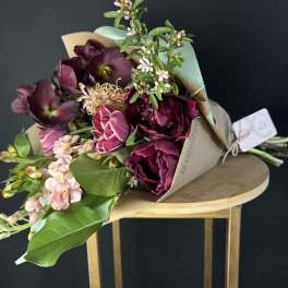 Bouquet of deep burgundy and pink flowers wrapped in kraft paper