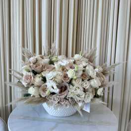 Blush and ivory rose arrangement in a white vase with pampas grass