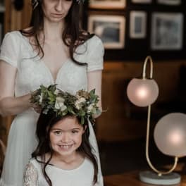 Bride adjusting a floral crown on a smiling girl in a white dress