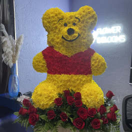 Winnie the Pooh floral sculpture with red roses at the base