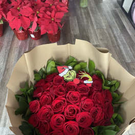 Bouquet of red roses wrapped in tan paper with a Grinch topper