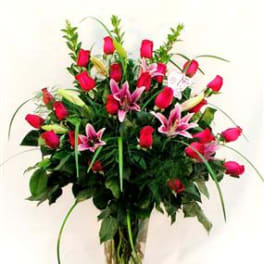 Bouquet of red roses and pink lilies in a clear glass vase
