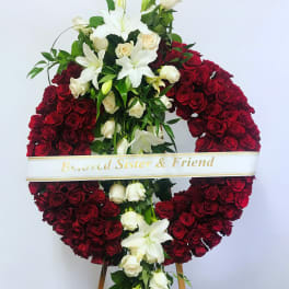 Heart-shaped red rose wreath with white lilies and a memorial ribbon