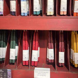Assorted taper candles in a red display shelf