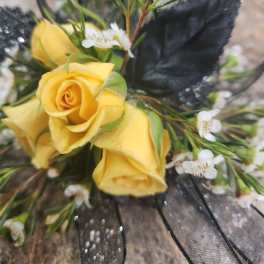 Yellow roses with small white filler flowers and black ribbon mesh