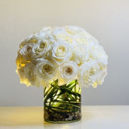 White rose bouquet in a glass vase with decorative stones