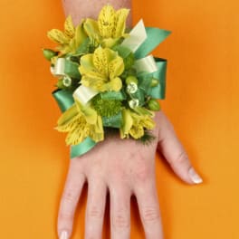 Yellow flower wrist corsage with green ribbon on a hand