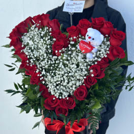 Heart-shaped bouquet of red roses with baby's breath and a teddy bear