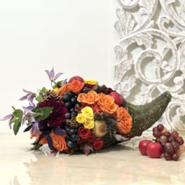 Horn-shaped floral arrangement with roses, grapes, and apples