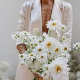 Woman holding a loose bouquet of white daisy-like flowers