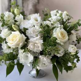 White roses and lisianthus arranged in a silver vase