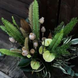 Arrangement with green anthuriums, fern fronds, and seed pods